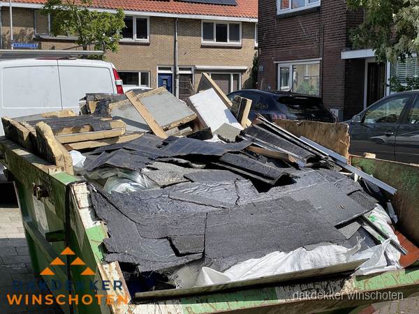 Afvalcontainer met gesloopt dakmateriaal tijdens dakkapel renovatie in Winschoten Afvalcontainer met gesloopt dakmateriaal tijdens dakkapel renovatie in Winschoten