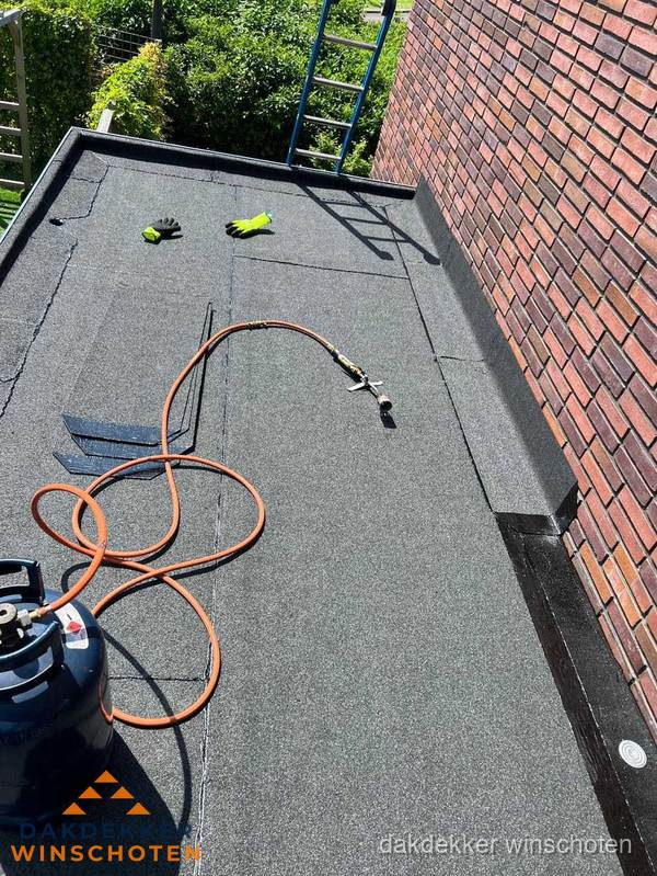 Plat dak met bitumen en brandgereedschap van dakdekkersbedrijf in Winschoten