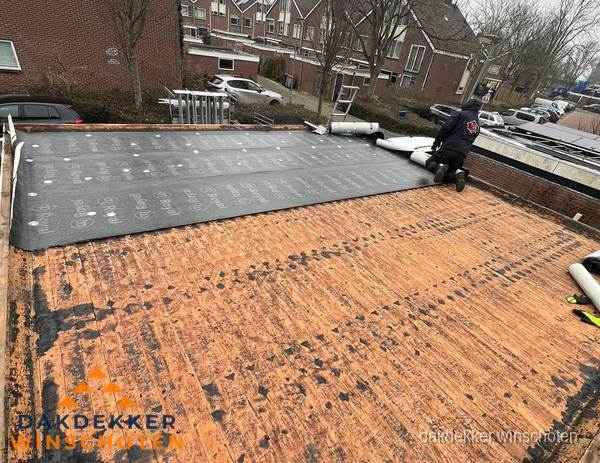 Dakdekker legt onderlaag op plat dak met houten constructie in Winschoten