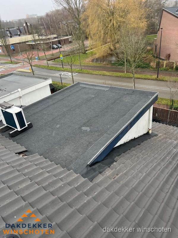 Plat dak met bitumen dakbedekking naast schuin pannendak in Winschoten