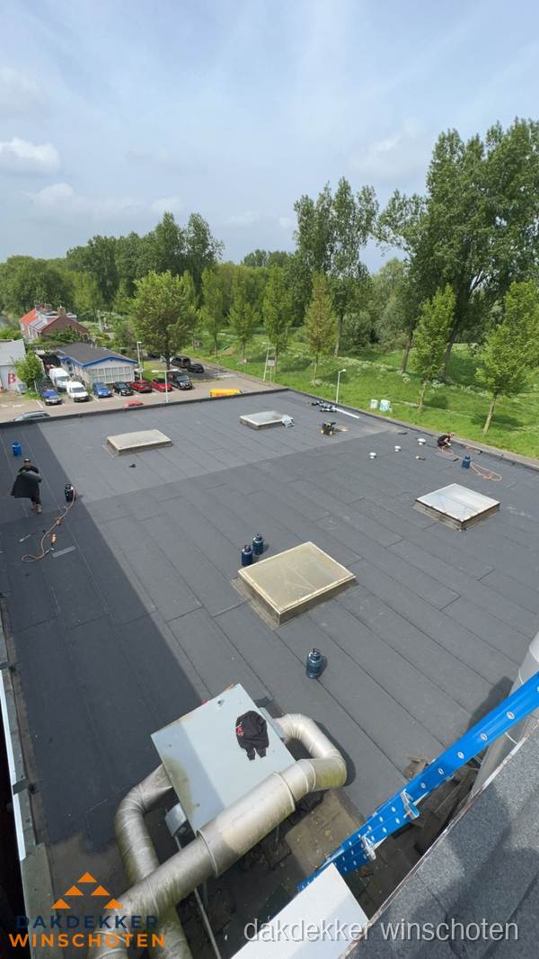 Dakdekker aan het werk op groot plat dak met bitumen in Winschoten Dakdekker aan het werk op groot plat dak met bitumen in Winschoten