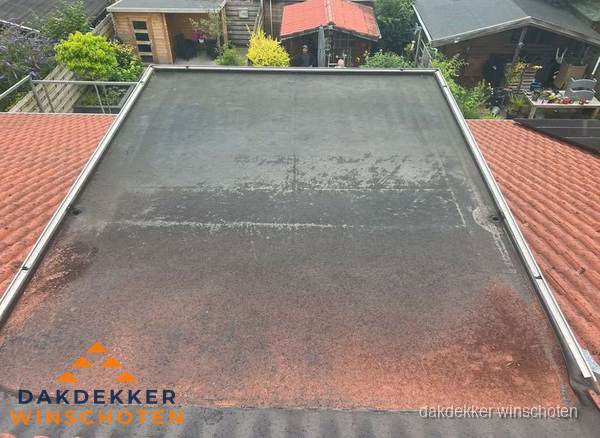 Verouderd plat dak met slijtage tussen schuine daken in Winschoten Verouderd plat dak met slijtage tussen schuine daken in Winschoten