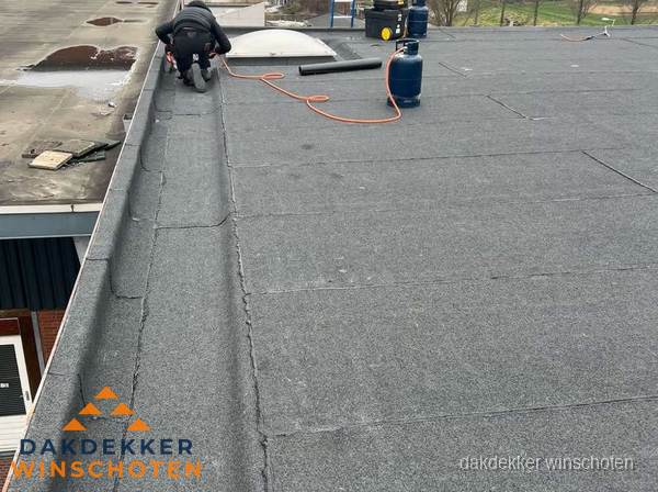 Dakdekker repareert bitumen dakbedekking op groot plat dak in Winschoten