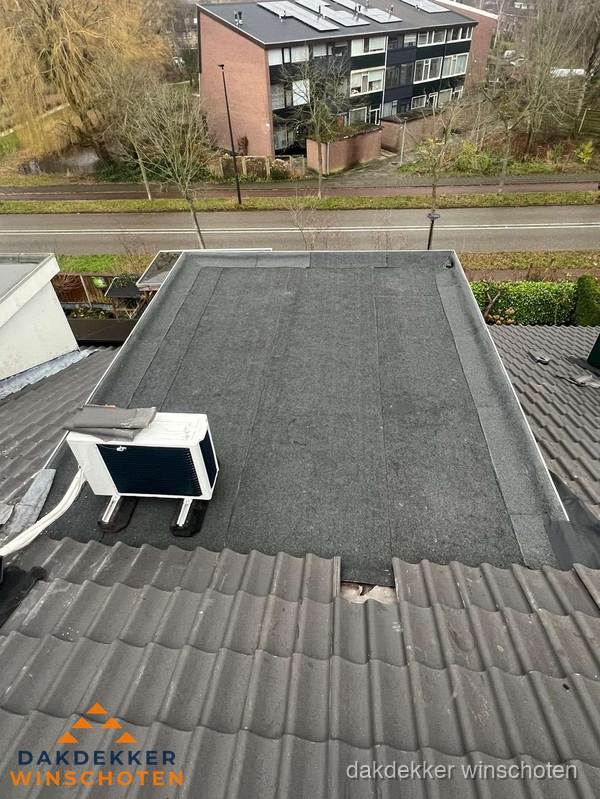 Plat dak inspectie met bitumen bedekking naast schuin pannendak in Winschoten