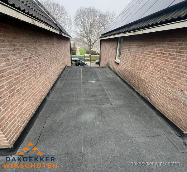 Plat dak met bitumen dakbedekking tussen bakstenen muren in Winschoten