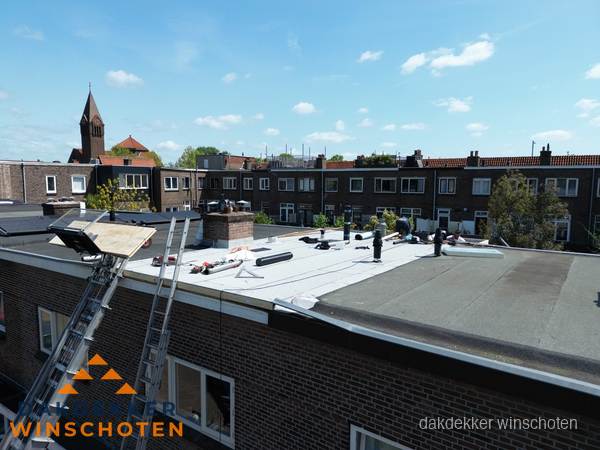 Dakdekkers aan het werk op plat dak in Winschoten